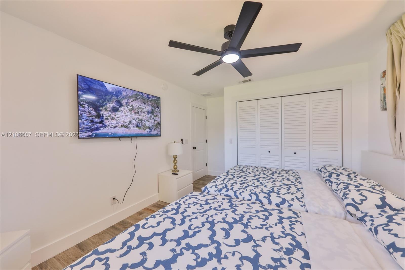 Wood-finish flooring, multi-blade ceiling fan with integrated lighting, and white bi-fold closet doors