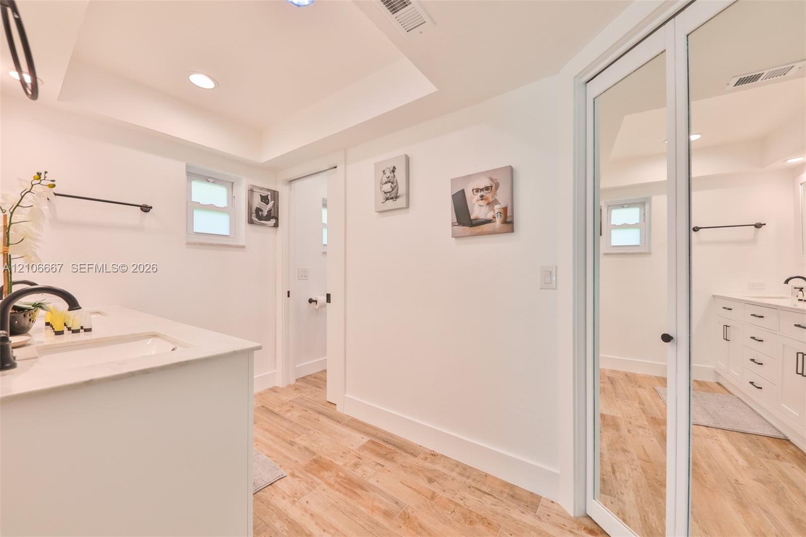 Bathroom featuring white cabinetry, stone-surface countertops, wood-finish flooring, recessed lighting, and a full-length mirrored closet door