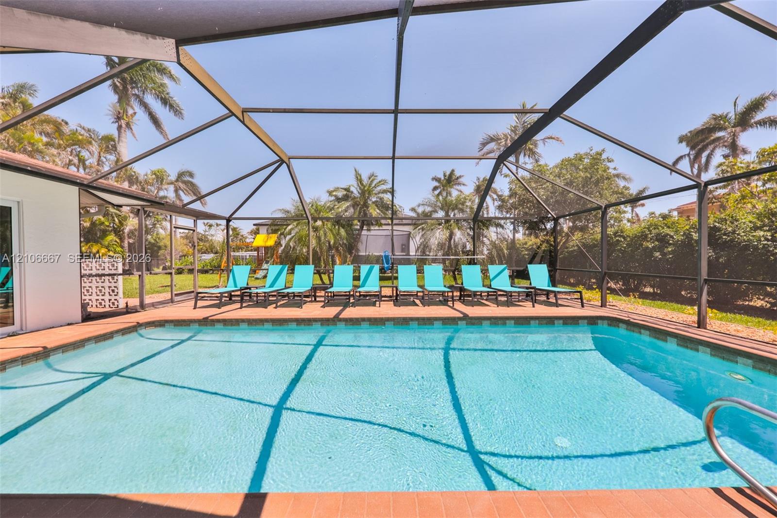 Screen-enclosed swimming pool featuring a paved pool deck and metal frame structure
