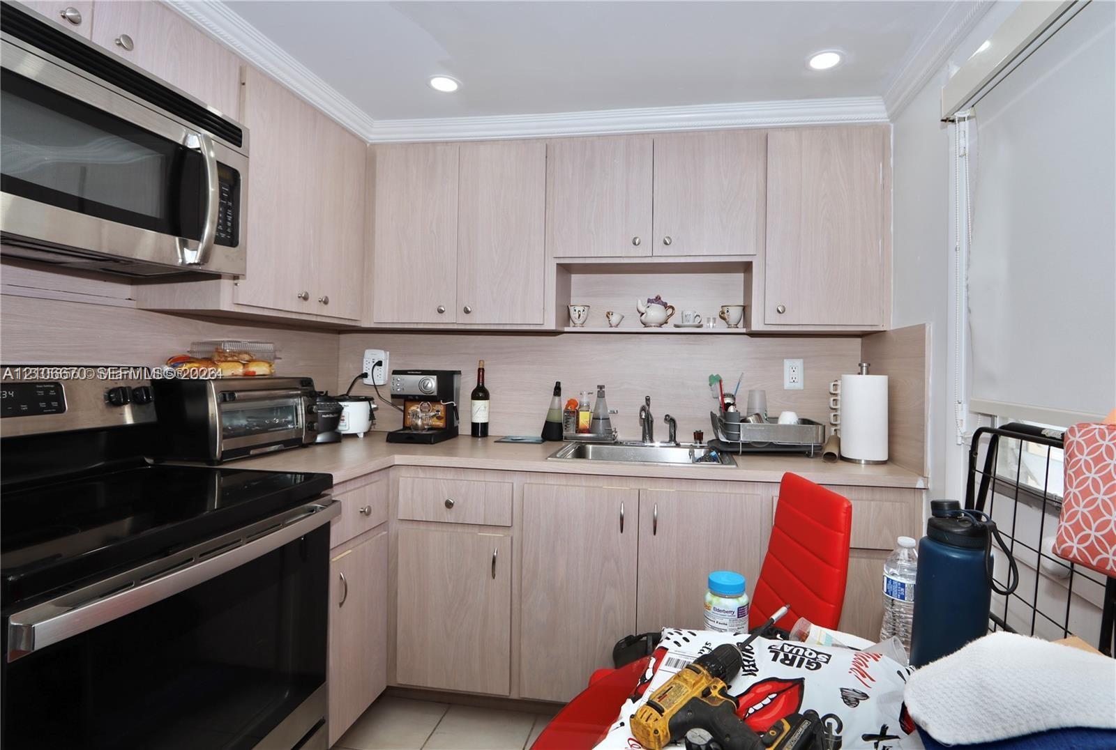Kitchen featuring light-finish cabinetry, stainless steel microwave, integrated oven, and a metal sink with a high-arch faucet