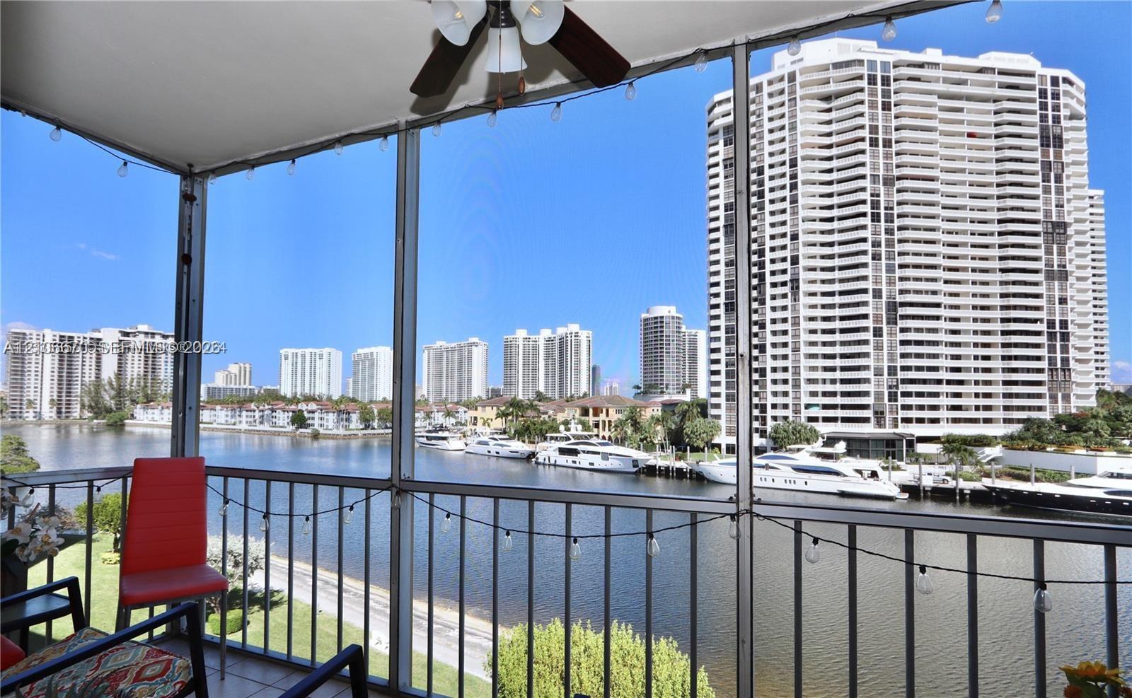 Screened-in balcony featuring a metal railing, overhead ceiling fan, and string lighting