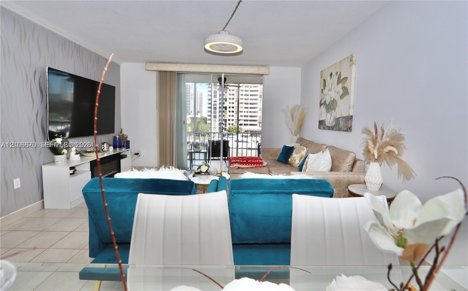 Living area featuring tile flooring, textured accent wall, integrated electric fireplace, and sliding glass door access to a balcony