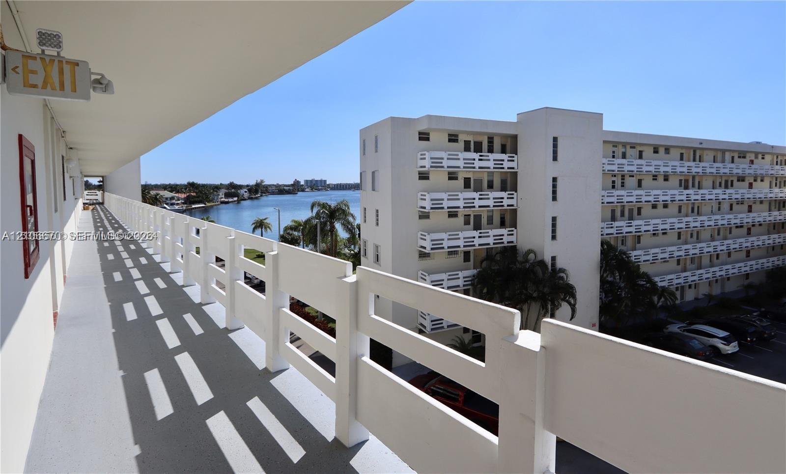 Covered exterior walkway with white metal railing and a waterfront outlook