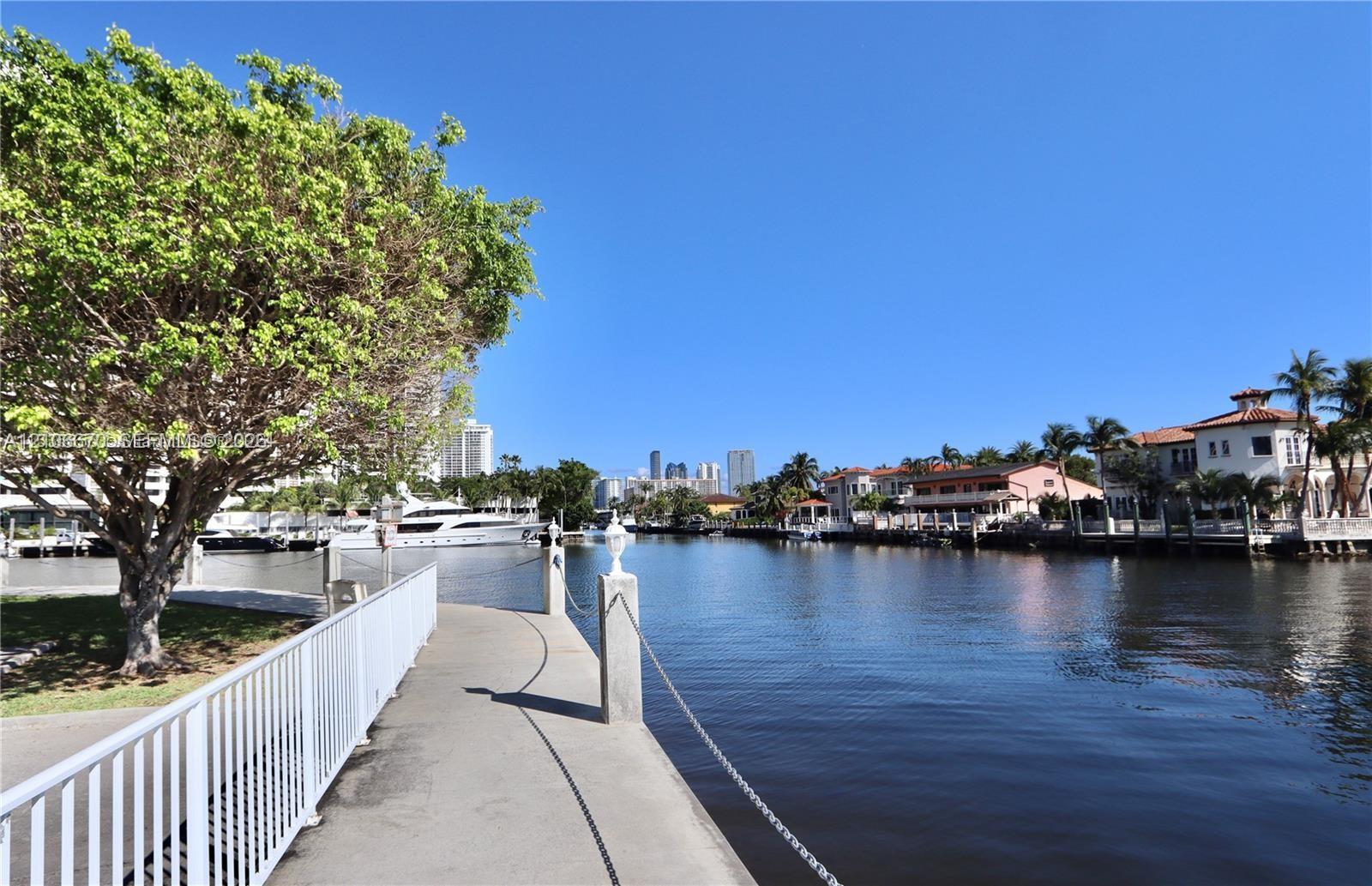 Waterfront walkway featuring metal railings, concrete paving, and mature trees