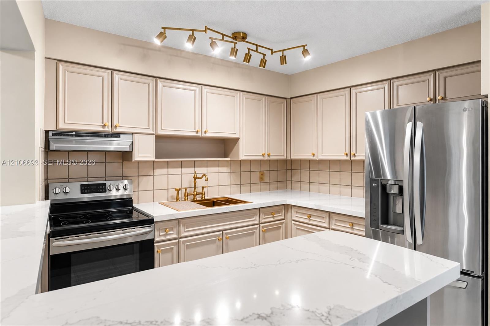 Kitchen featuring quartz countertops, shaker-style cabinetry, a multi-light directional ceiling fixture, stainless steel appliances, and a tiled backsplash Kitchen featuring quartz countertops, shaker-style cabinetry, a multi-light directional ceiling fixture, stainless steel appliances, and a tiled backsplash