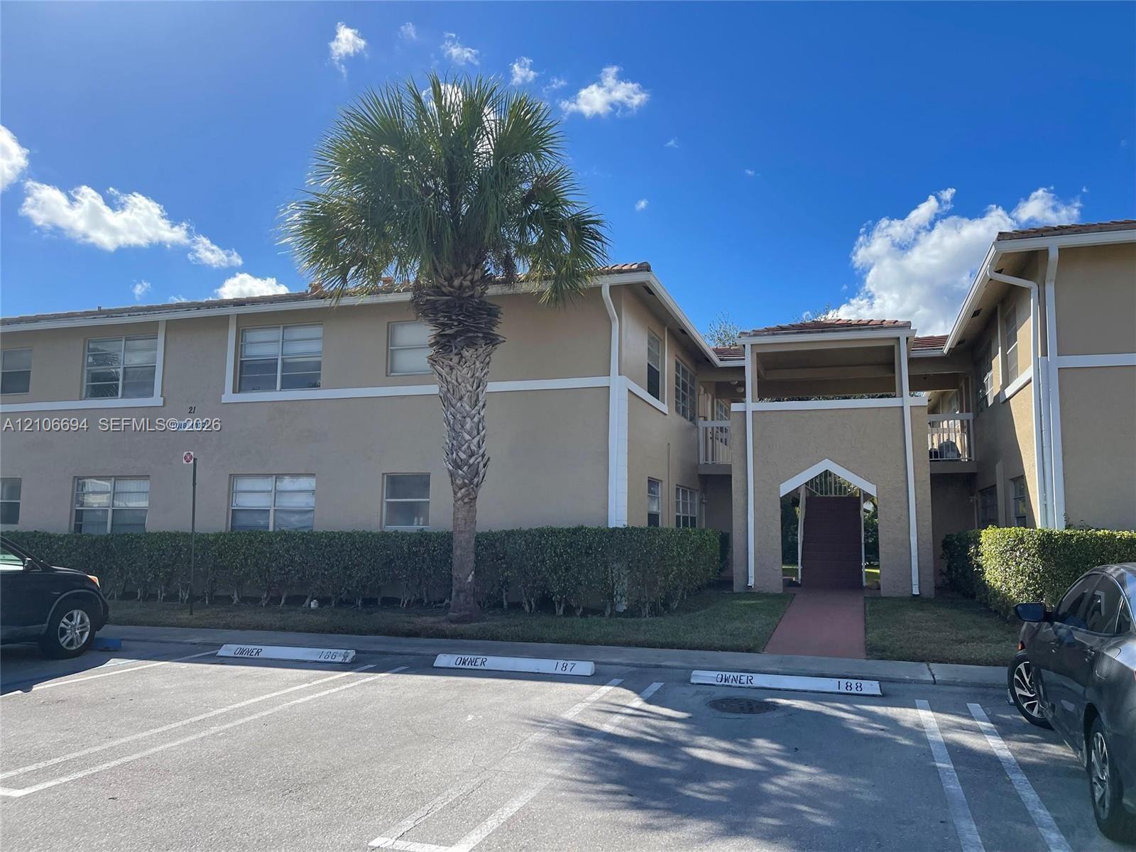 Stucco exterior building featuring a tiled roofline, covered entryway, and dedicated parking spaces