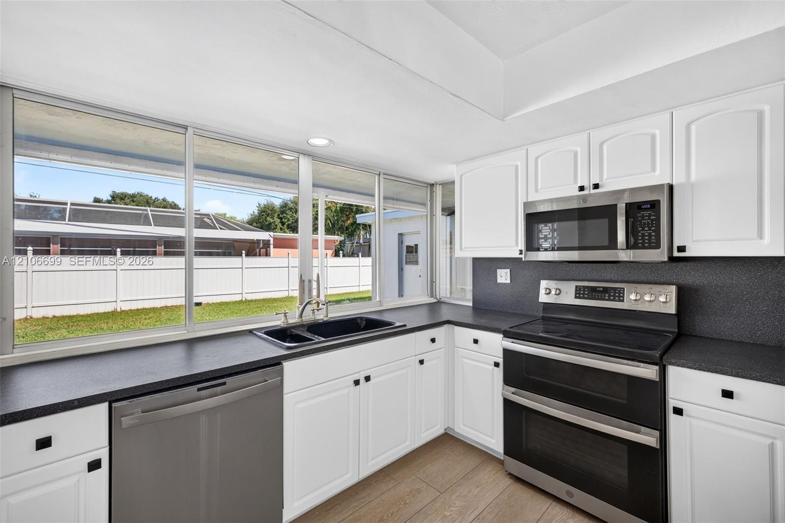 Open concept kitchen w/ updated plank wood look tile, stainless appliances approx 2020
