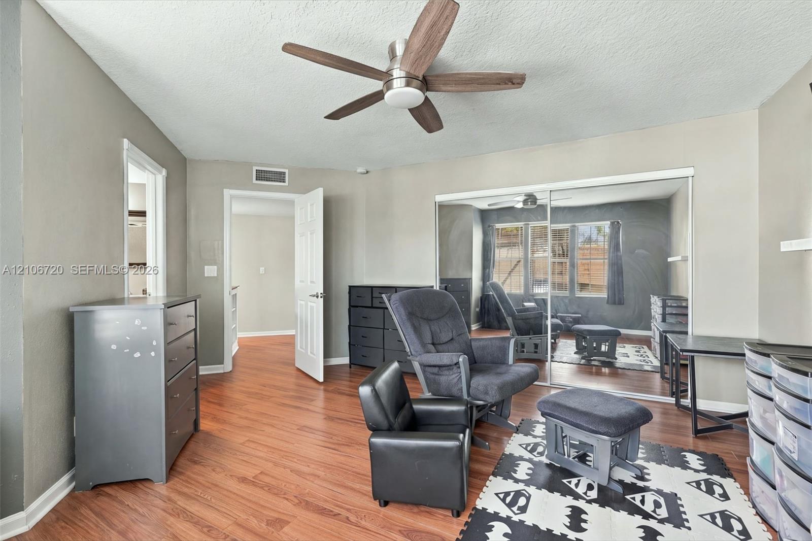 Wood-finish flooring, ceiling fan with integrated lighting, and wall-to-wall sliding mirrored closet doors