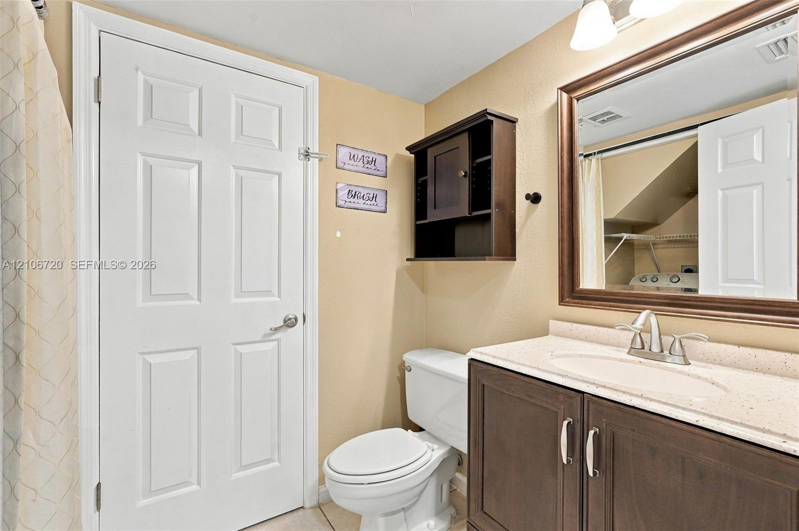 Bathroom featuring a vanity with a light-toned solid surface countertop, an oval undermount sink, a framed wall mirror, and dark-finish built-in cabinetry