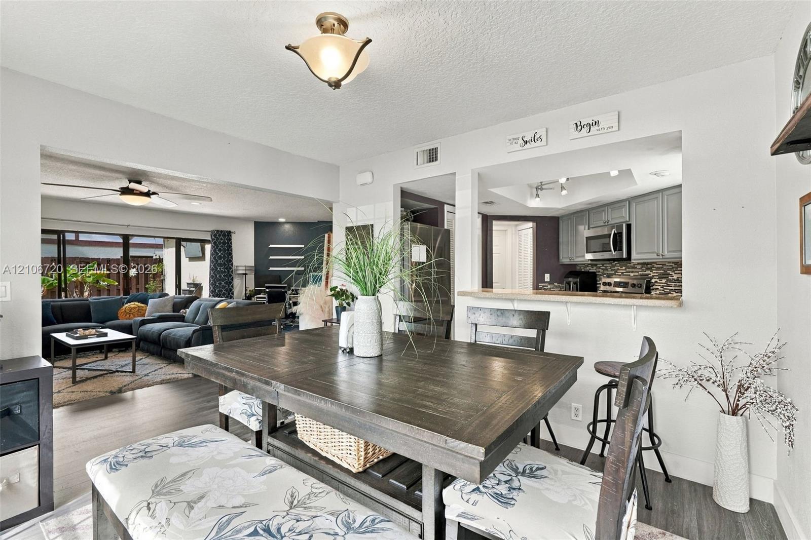 Dining area featuring wood-finish flooring, a pass-through opening to the kitchen, and a flush-mount light fixture