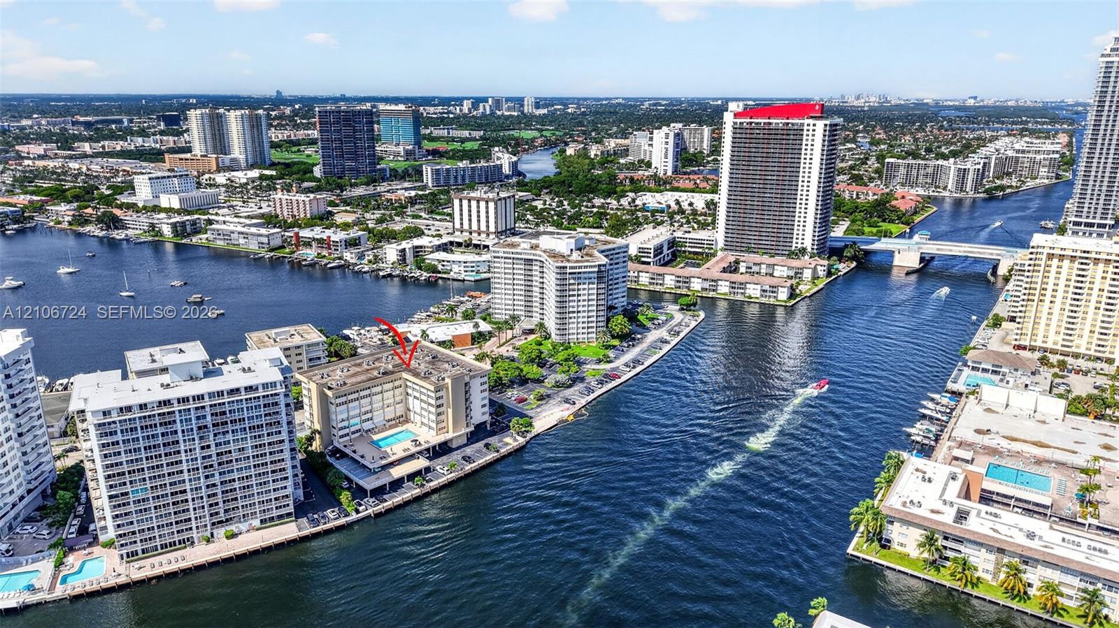 Waterfront mid-rise building featuring a ground-level pool, surface parking, and direct maritime canal access