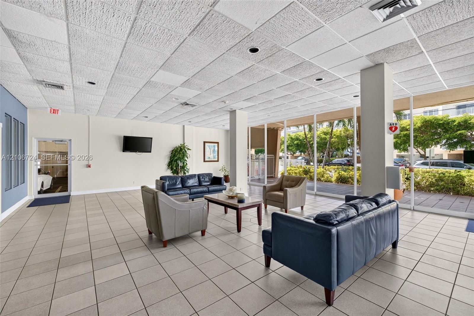 Open-concept common area featuring large floor-to-ceiling windows, uniform tile flooring, recessed lighting, and a neutral color palette