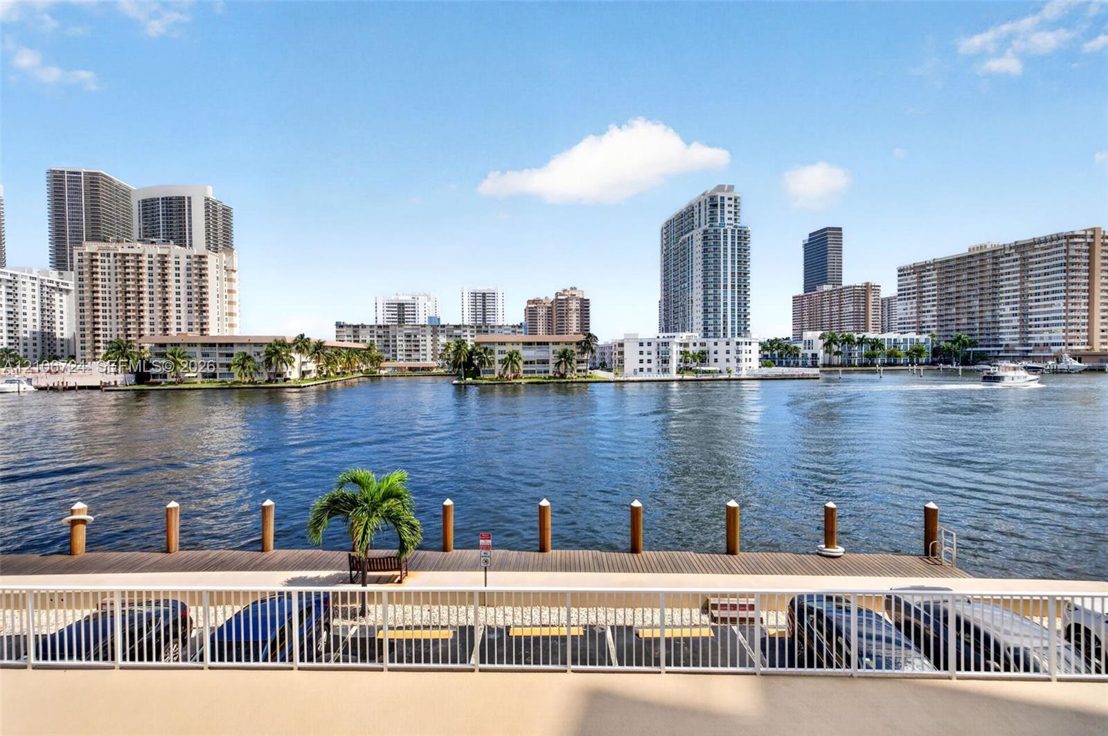 Waterfront deck featuring a wooden bulkhead, piling moorings, and a metal safety railing