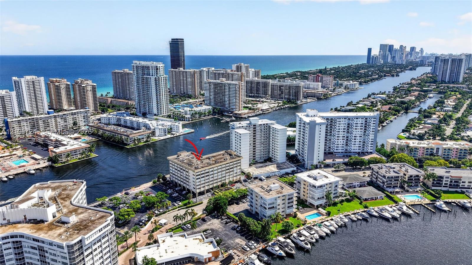 Aerial perspective of a multi-story waterfront building featuring direct canal access, docking facilities, and proximity to the coastline