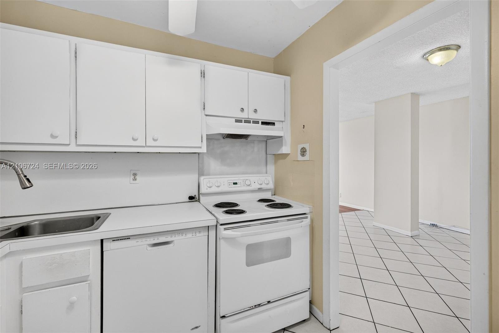Kitchen featuring white cabinetry, solid-surface countertops, integrated stainless steel sink with gooseneck faucet, white electric range, and dishwasher