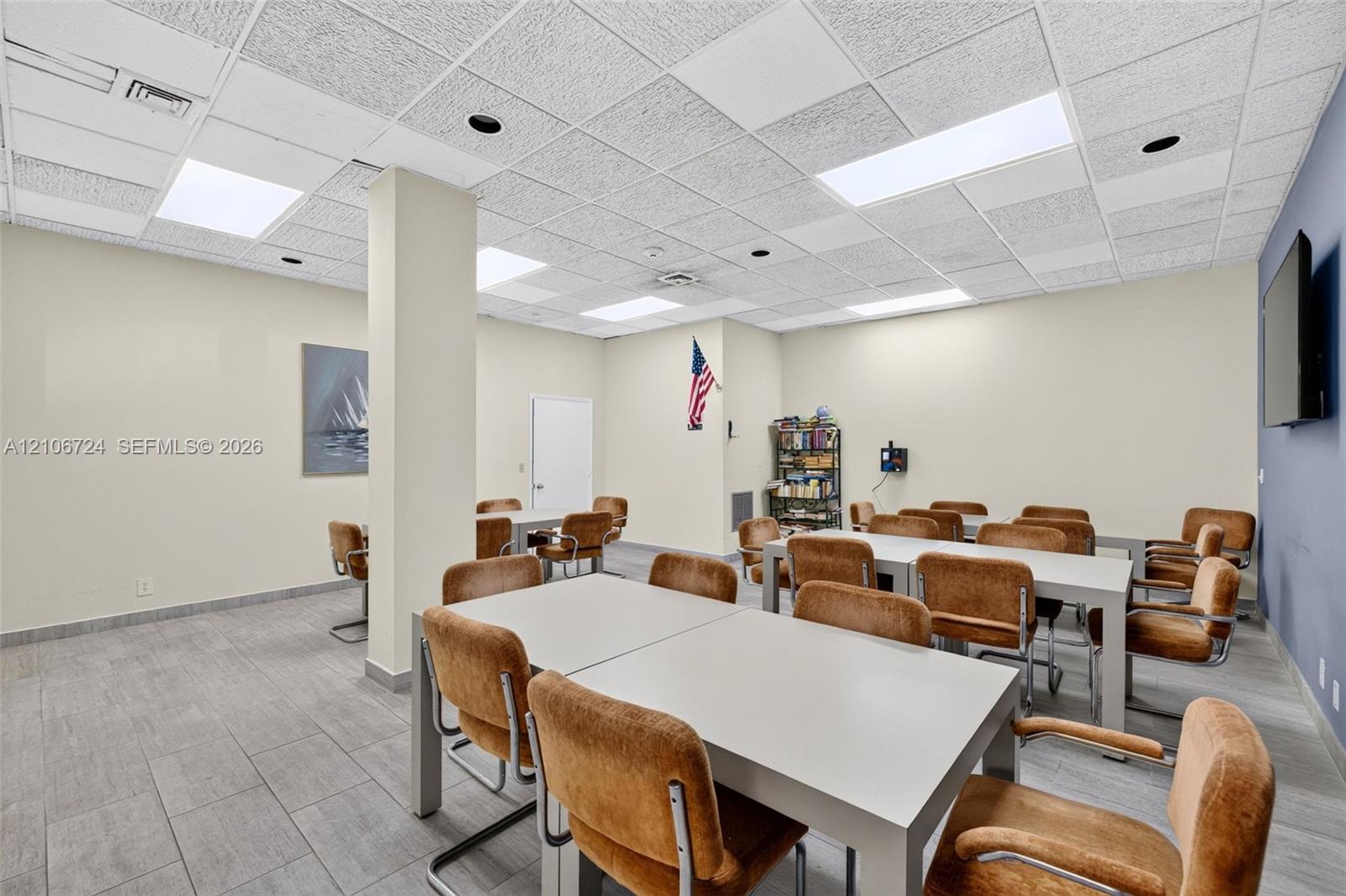 Open-concept interior featuring drop ceiling tiles with recessed lighting, structural support column, and gray tile flooring