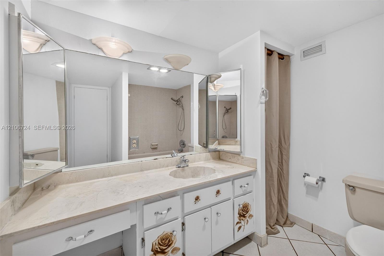 Bathroom featuring a stone-surface vanity with an integrated basin, a large multi-panel mirror, ceramic tile flooring, and a combined tub and shower surround