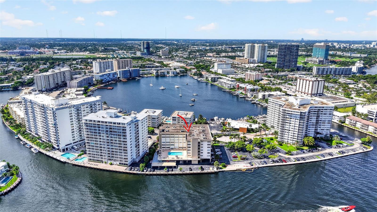 Aerial perspective of waterfront mid-rise building featuring a swimming pool, bulkhead shoreline, and direct water access