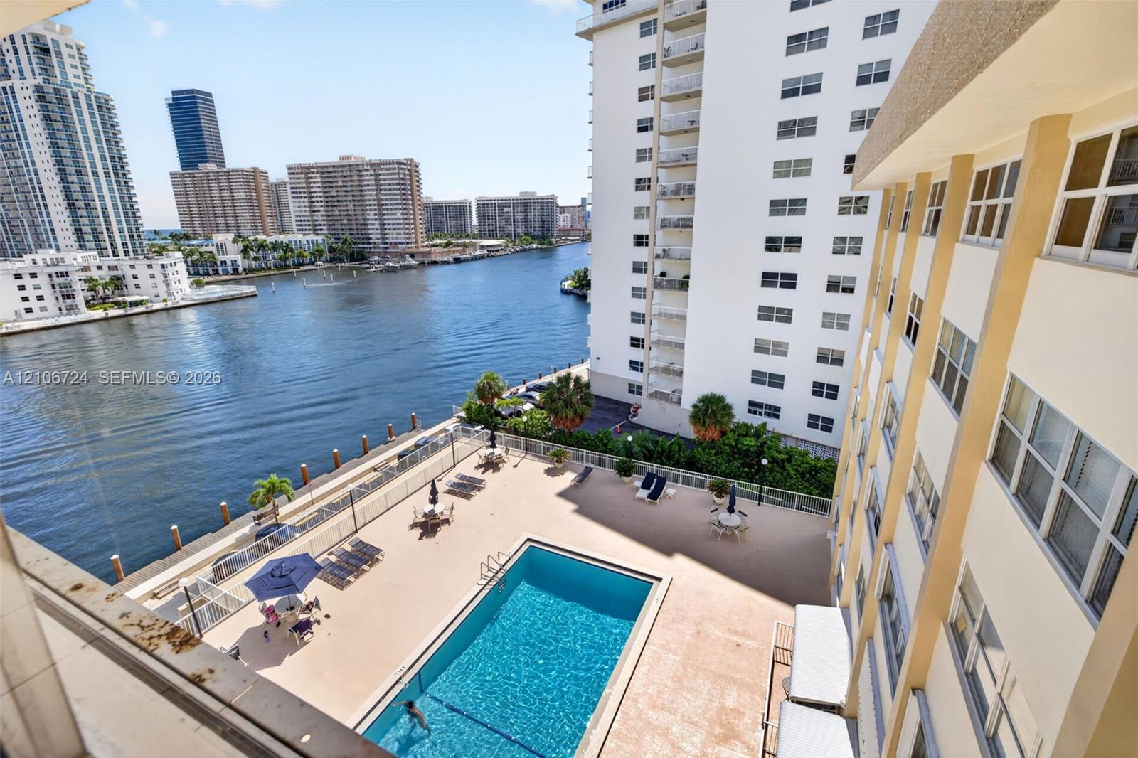 Ground-level swimming pool featuring a paved pool deck and bulkhead waterfront access overlooking the waterway