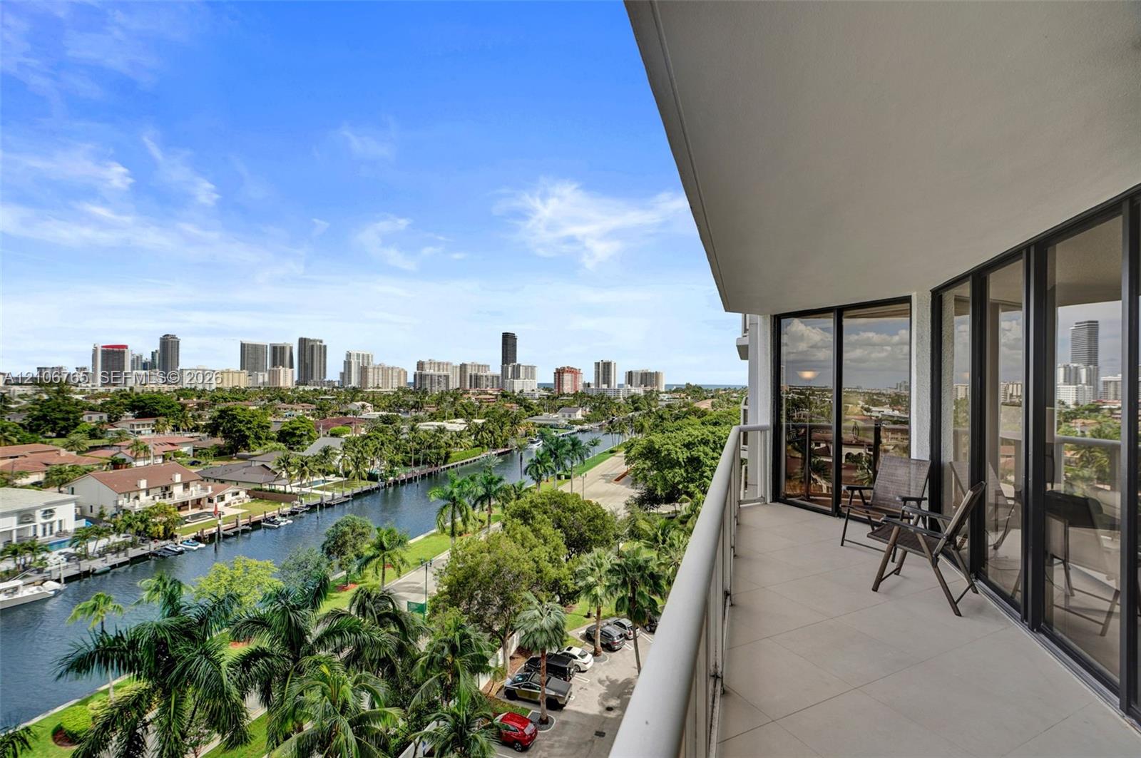 Covered balcony with large-format tile flooring, glass-panel railing, and floor-to-ceiling sliding glass doors