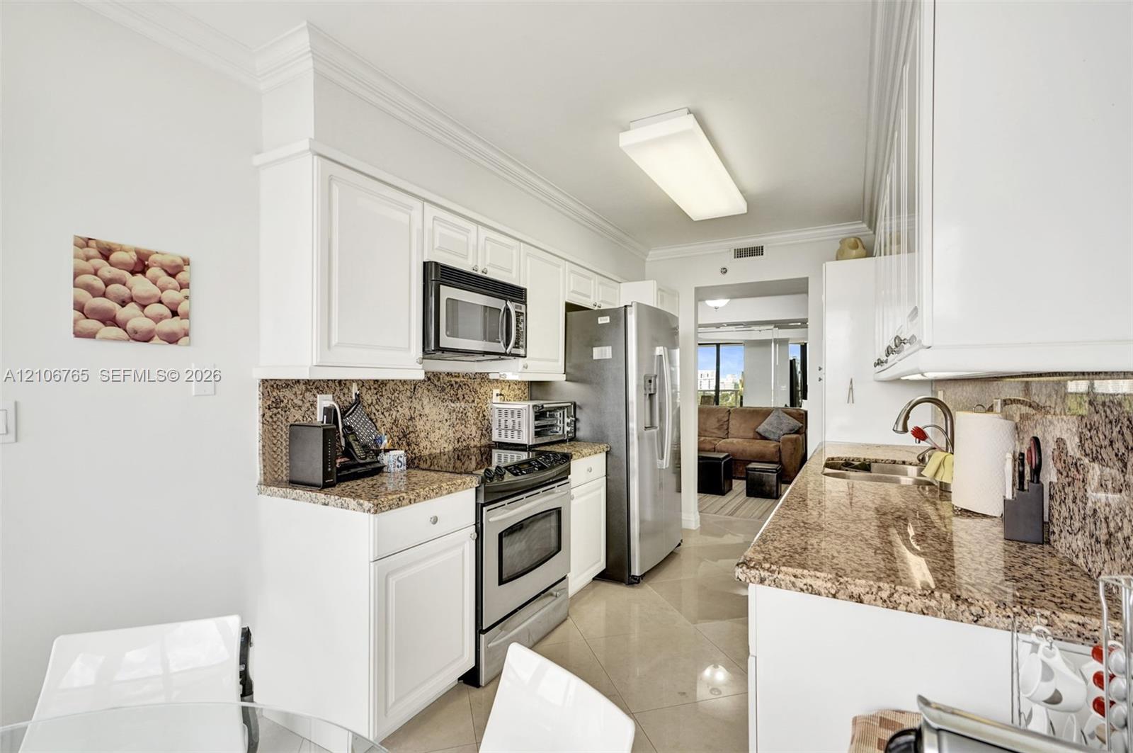 White cabinetry, stone countertops, stone tile backsplash, stainless steel appliances.