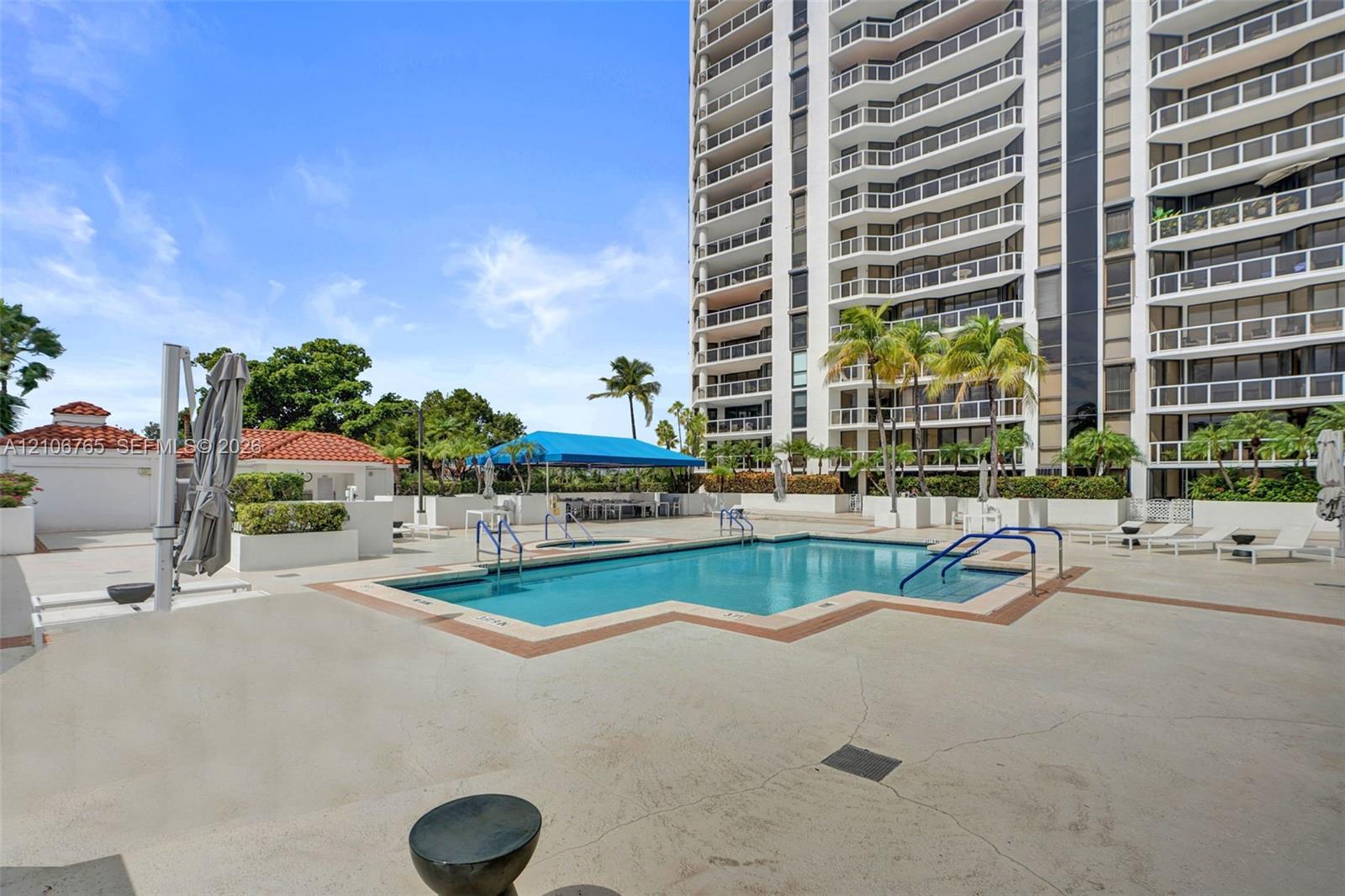 Swimming pool with integrated stair entry, surrounding concrete deck, shaded cabana area, and palm tree landscaping