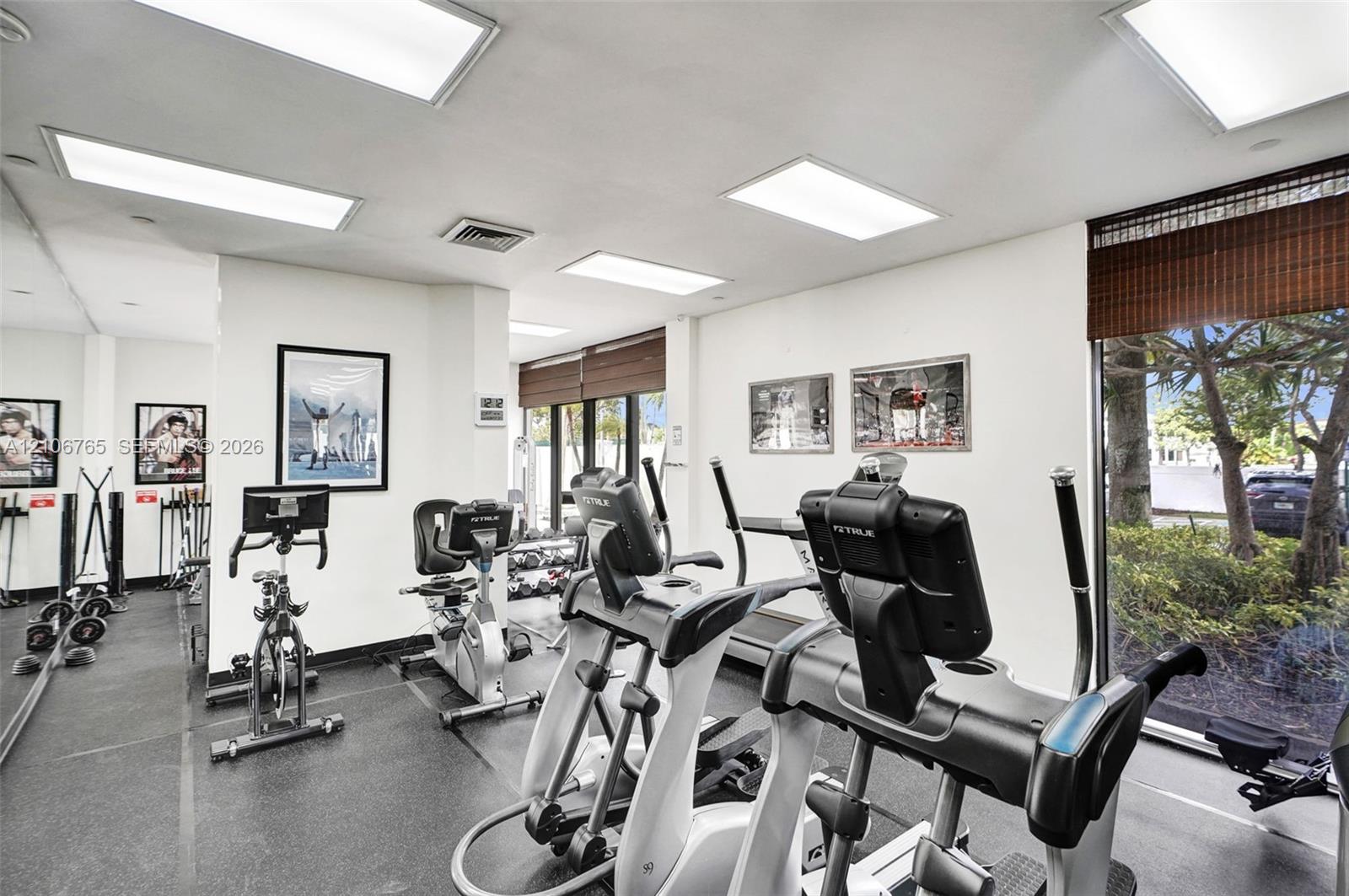 Fitness center featuring recessed panel lighting, floor-to-ceiling mirror wall, and floor-to-ceiling windows with integrated window shades