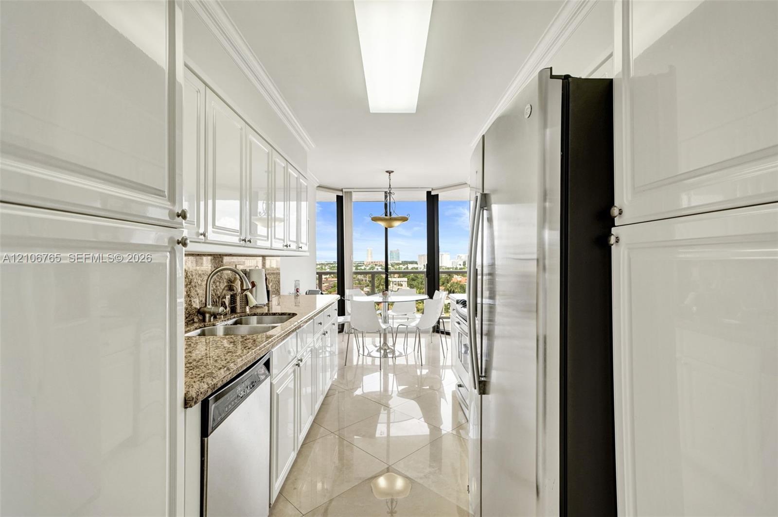 Kitchen with white cabinetry, stone countertops, stainless steel appliances, and ceramic floors.