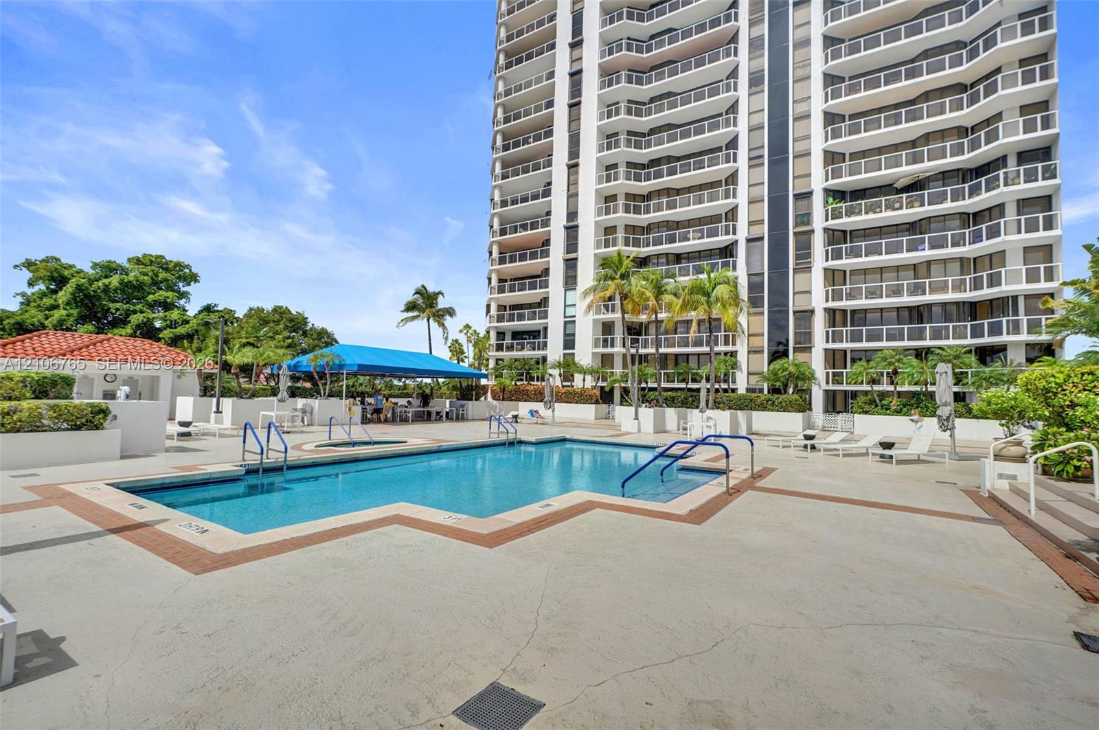 Swimming pool featuring a concrete deck, built-in stair entry, attached shade structure, and surrounding landscaped grounds