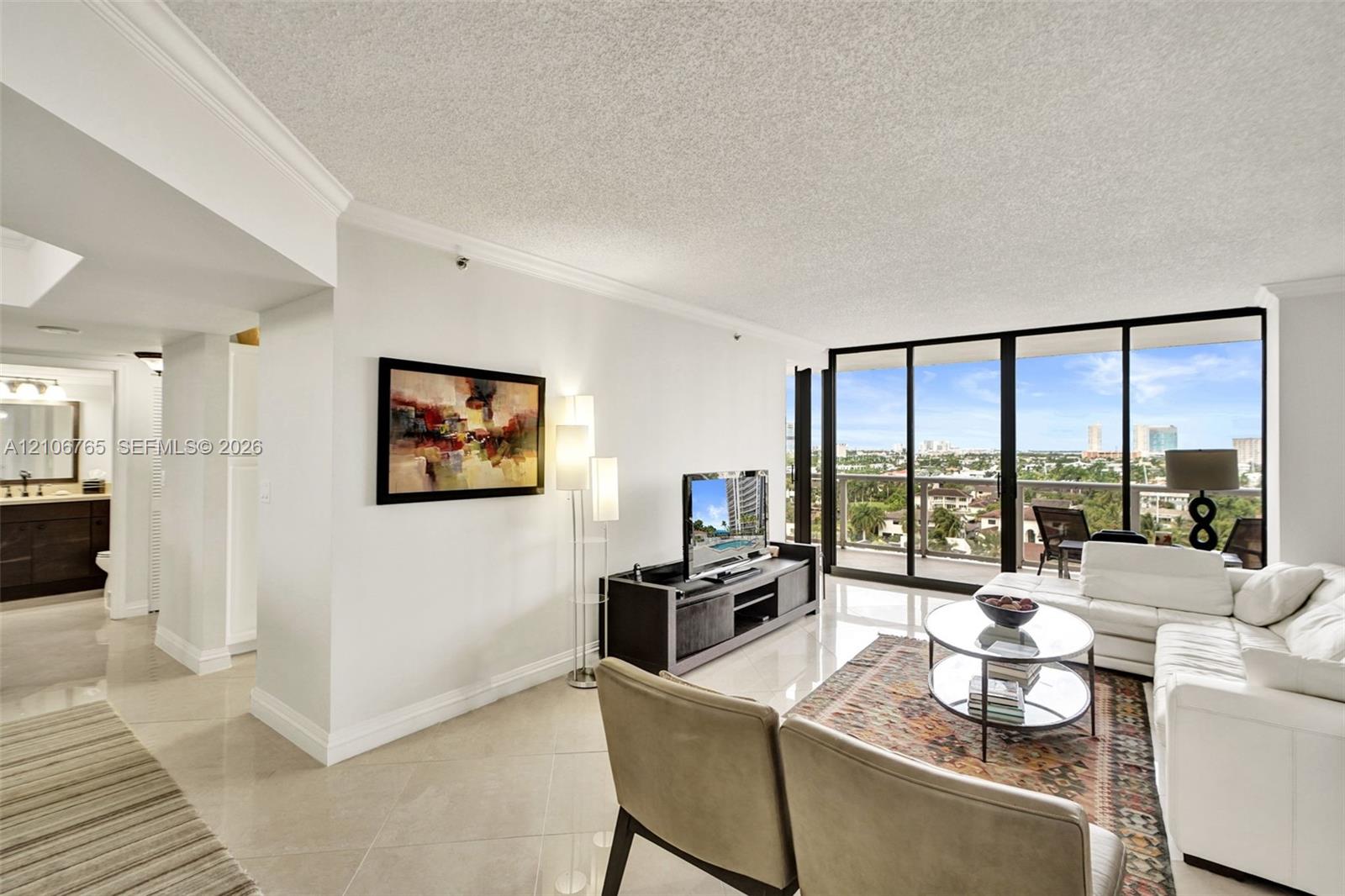 Living area, large tiles, floor-to-ceiling glass sliding doors opening to an exterior balcony. Living area, large tiles, floor-to-ceiling glass sliding doors opening to an exterior balcony.
