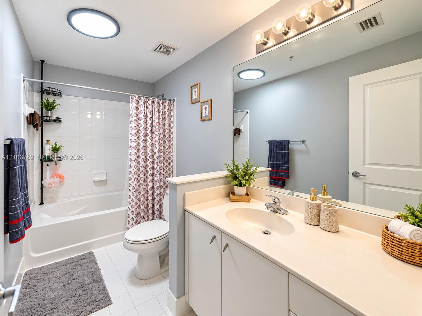 Bathroom featuring a vanity with a solid-surface countertop, an integrated sink, a full-width vanity mirror, a bathtub-shower combination with tile surround, and recessed ceiling lighting