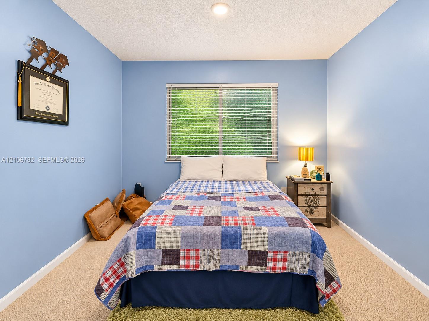Bedroom with neutral carpeting, horizontal window blinds, and a central ceiling light fixture