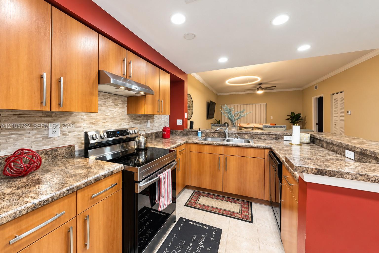 Kitchen featuring medium-tone wood cabinetry, stone-finish countertops, stainless steel range with a built-in exhaust hood, recessed lighting, and a linear tile backsplash