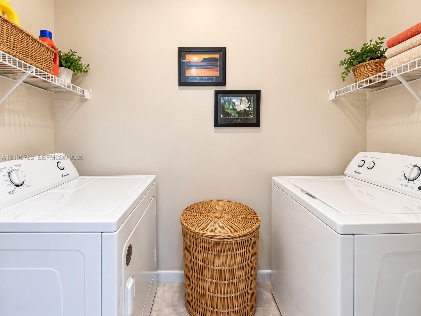 Laundry area featuring dual white appliances and white wire shelving