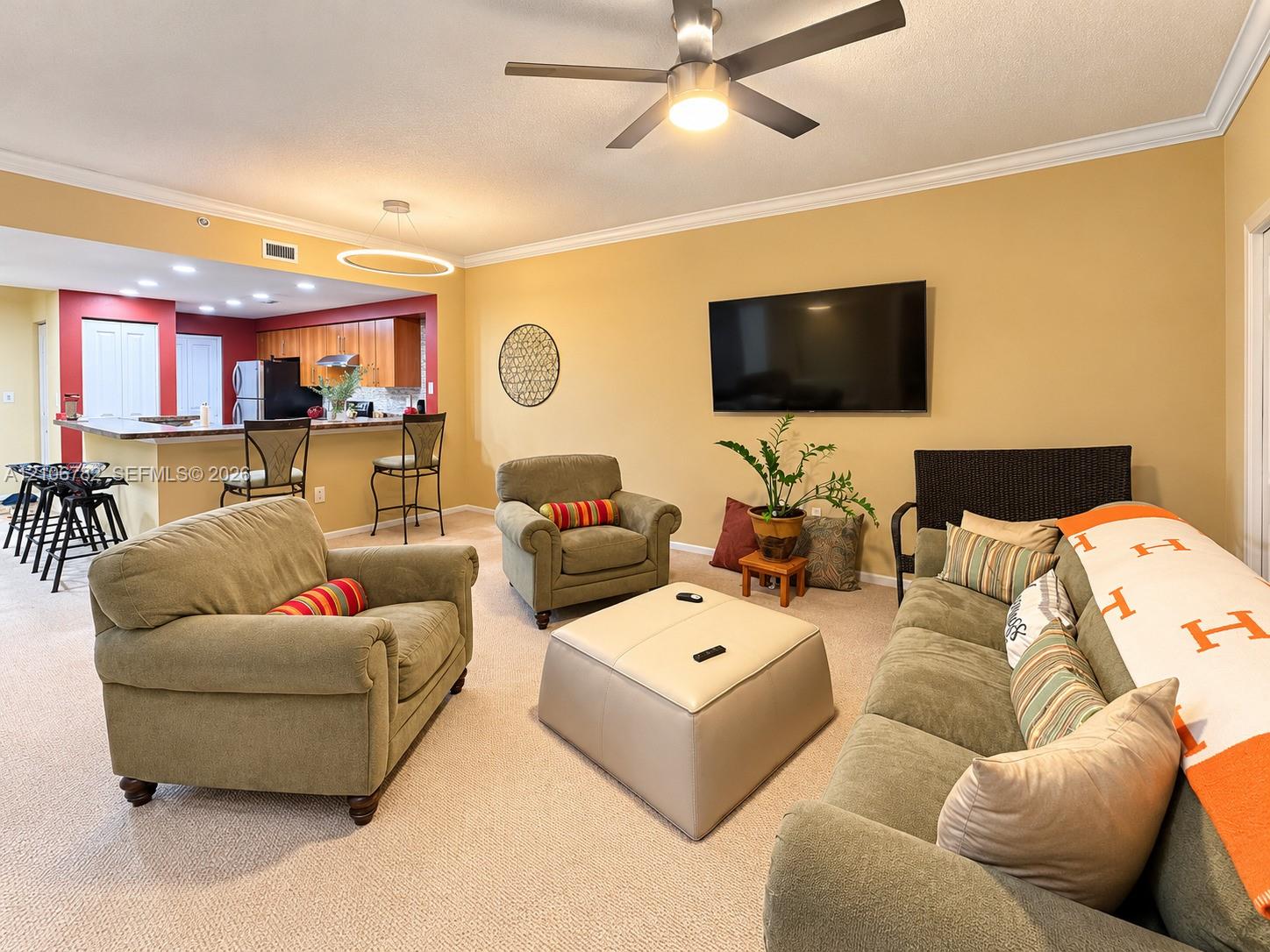 Open-concept floor plan featuring a kitchen breakfast bar, recessed lighting, crown molding, and a ceiling fan
