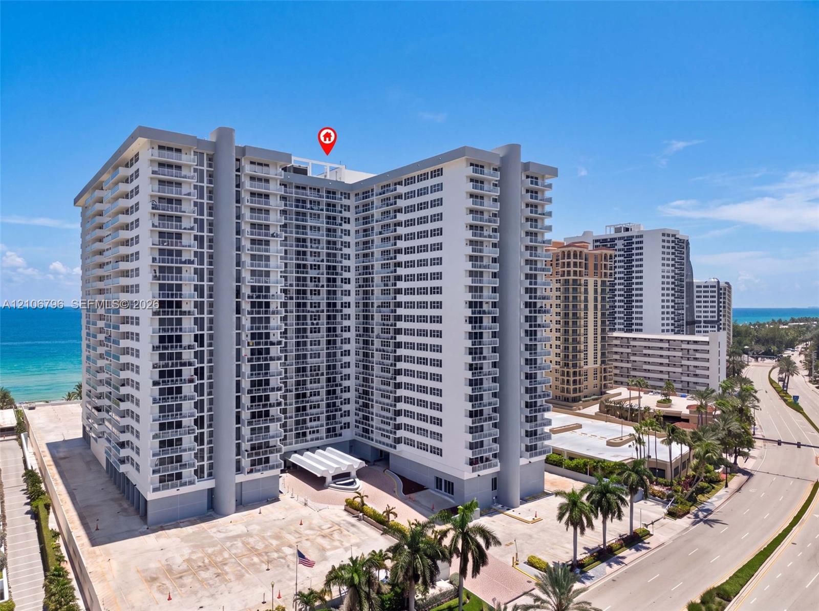 High-rise residential building featuring expansive private balconies, a porte-cochere entrance, and coastal ocean frontage
