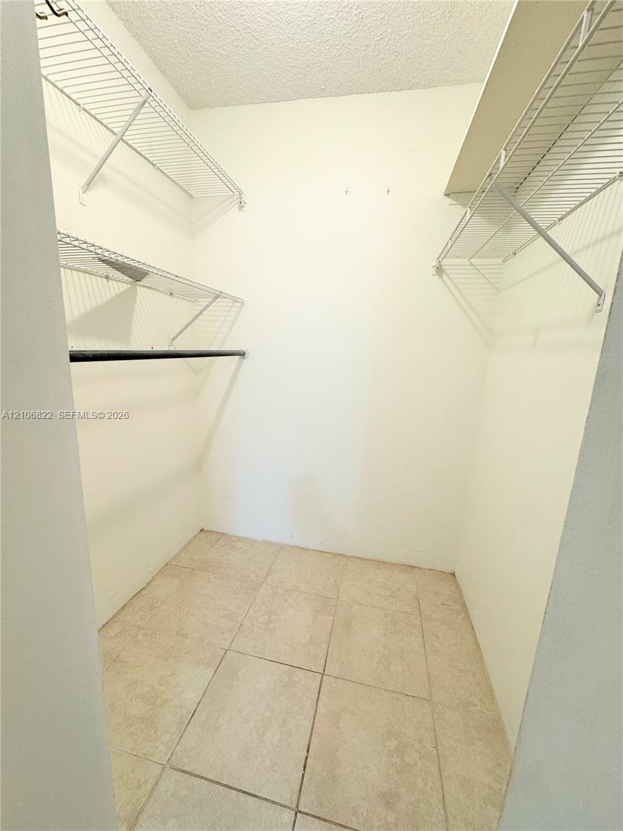 Storage space featuring ceramic tile flooring, multi-level wire shelving, and built-in hanging rods