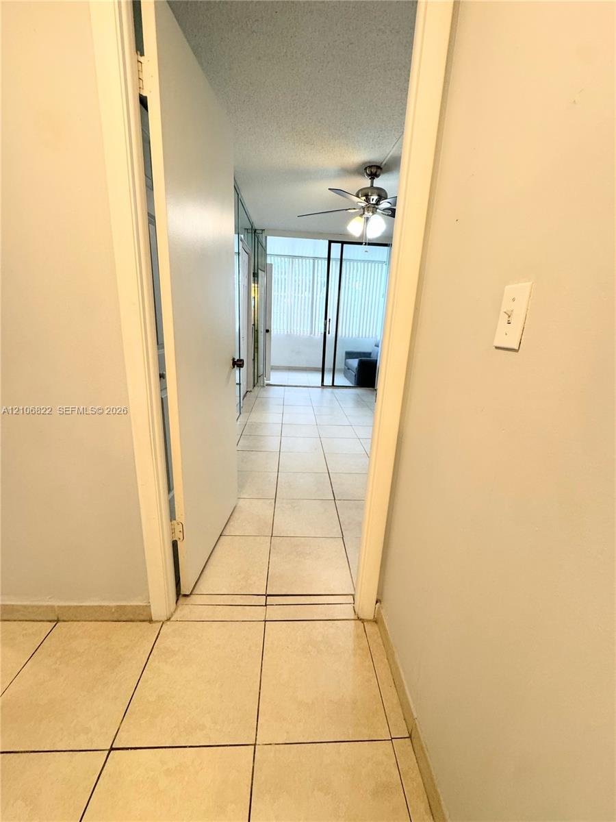 Interior space featuring large-format ceramic tile flooring, a multi-blade ceiling fan with integrated lighting, and a sliding glass door system