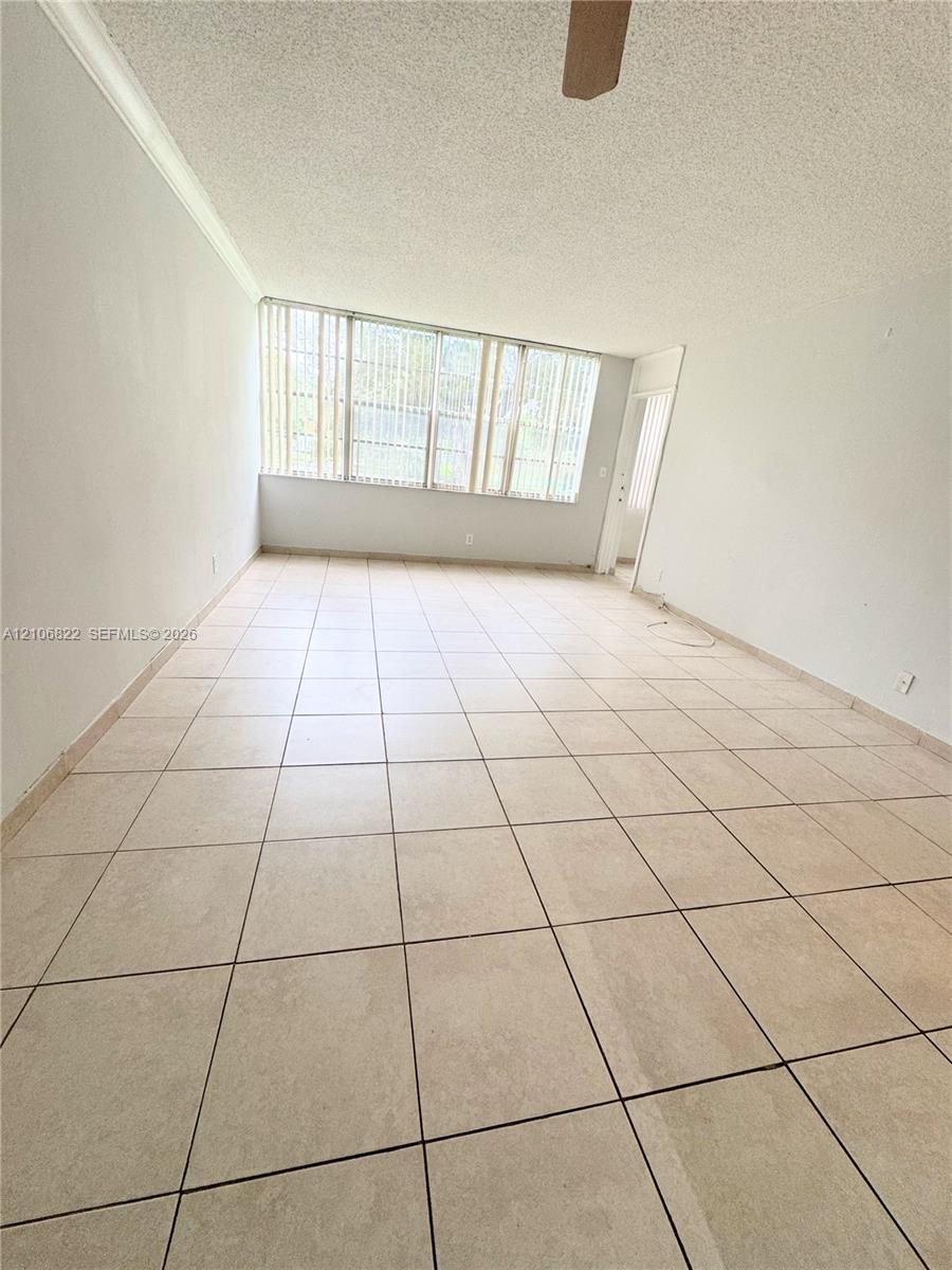 Interior space featuring large-format ceramic tile flooring, neutral walls, and extensive window groupings equipped with vertical blinds