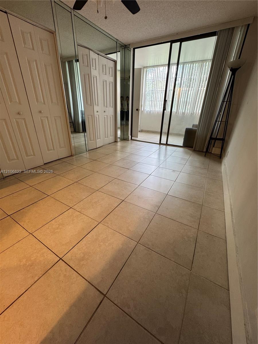 Ceramic tile flooring, floor-to-ceiling mirrored closet doors, and sliding glass doors leading to an enclosed balcony