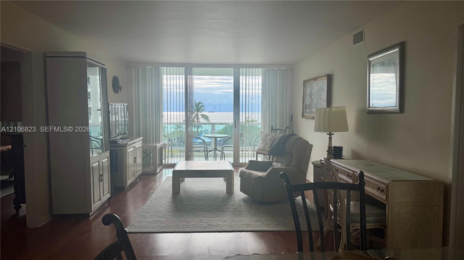 Living area featuring wood-finish flooring, floor-to-ceiling sliding glass doors, and direct access to an exterior balcony