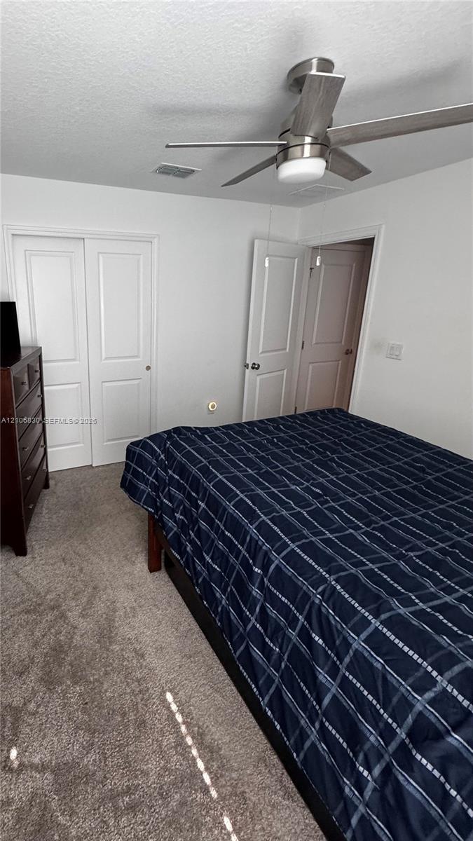 Neutral-toned wall-to-wall carpeting, brushed-nickel ceiling fan with integrated lighting, dual-panel closet doors, and multi-panel interior doors