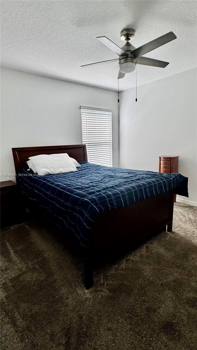 Neutral-toned walls, plush wall-to-wall carpeting, brushed-nickel ceiling fan with integrated lighting, and horizontal window blinds