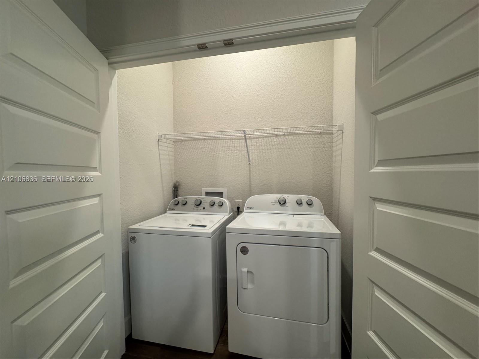 Laundry closet featuring dual panel doors and a wire storage shelf
