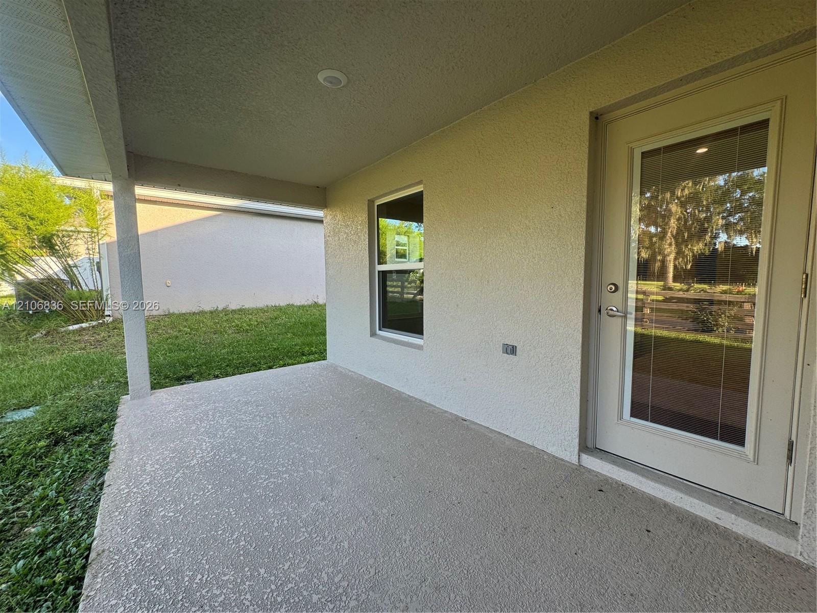 Covered concrete patio featuring stucco exterior siding, single-hung window, and glass-panel entry door with recessed lighting