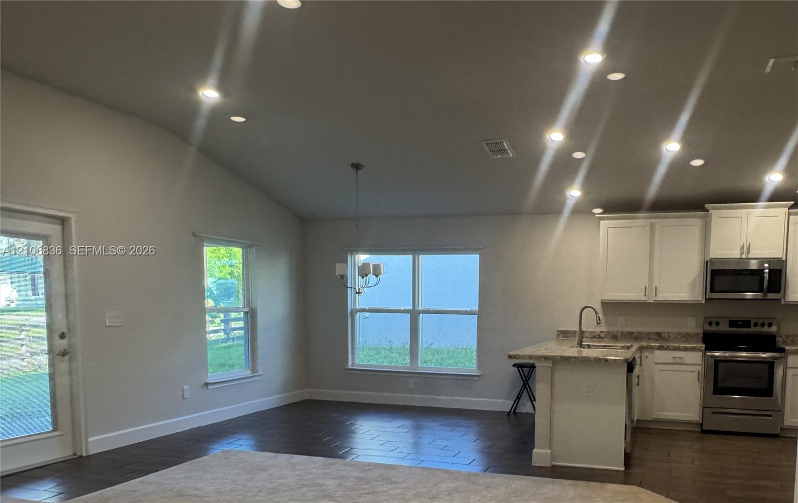 Vaulted ceilings with recessed lighting, wood-finish flooring, white cabinetry, integrated stainless steel appliances, and multi-paned windows Vaulted ceilings with recessed lighting, wood-finish flooring, white cabinetry, integrated stainless steel appliances, and multi-paned windows
