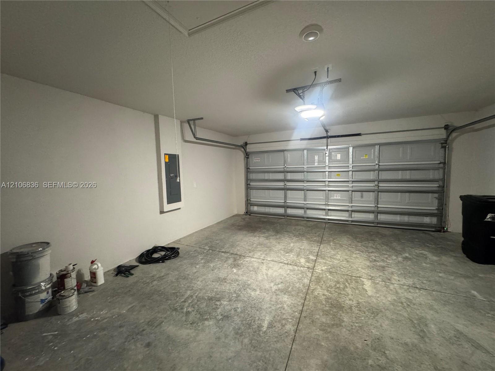 Two-car garage featuring a sectional overhead door, concrete flooring, and an integrated electrical panel