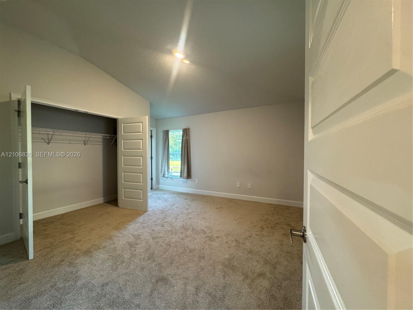 Vaulted ceilings, neutral carpeting, multi-panel interior doors, and a closet with wire shelving