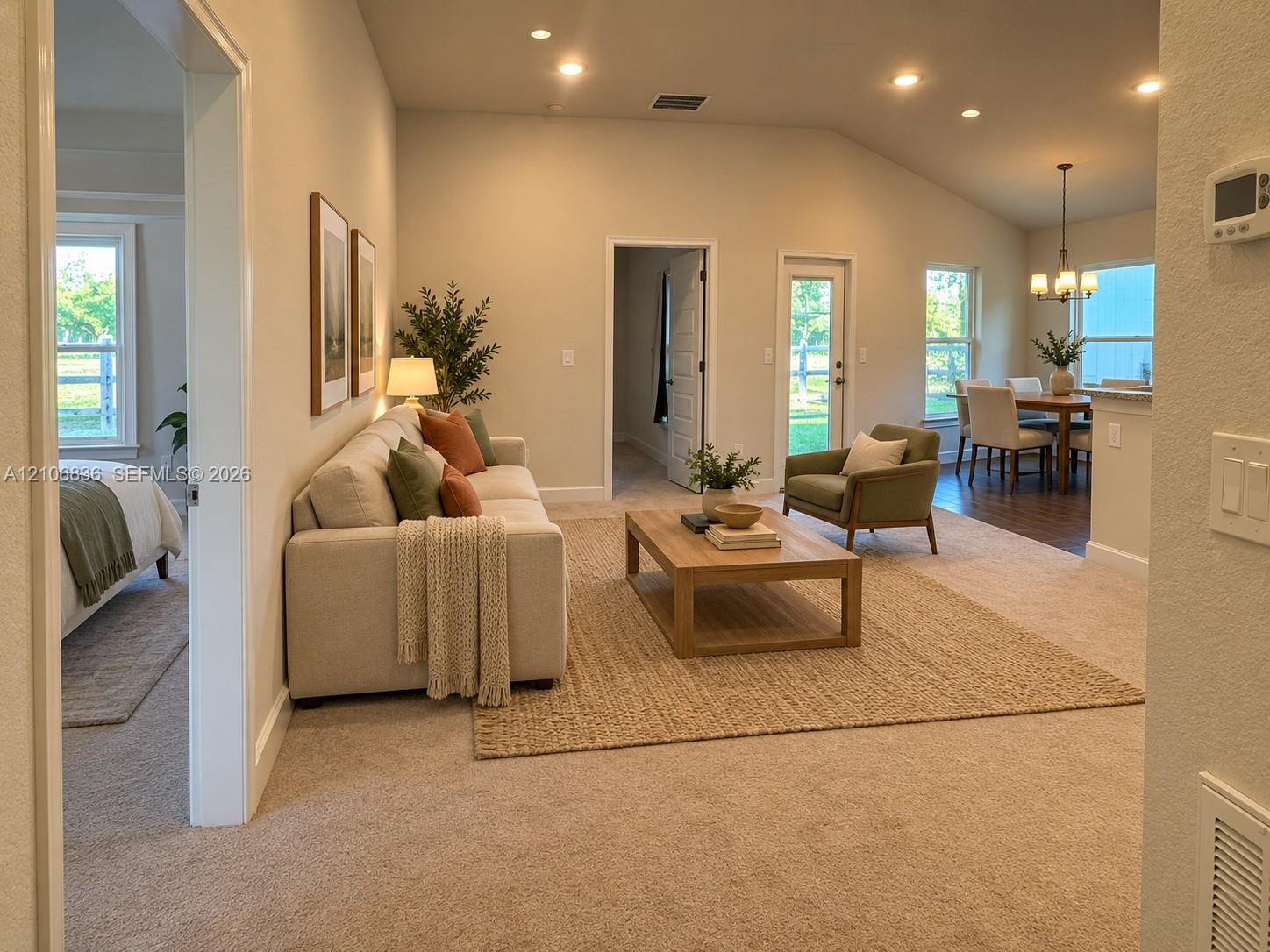 Open-concept interior featuring vaulted ceilings, recessed lighting, neutral carpeting, and a glass-paneled exterior door Open-concept interior featuring vaulted ceilings, recessed lighting, neutral carpeting, and a glass-paneled exterior door