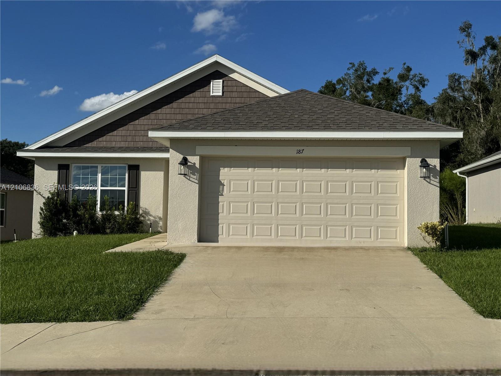 Single-story exterior featuring light-toned stucco siding, decorative shake-style gable accent, asphalt shingle roof, and a two-car garage Single-story exterior featuring light-toned stucco siding, decorative shake-style gable accent, asphalt shingle roof, and a two-car garage